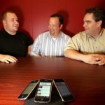 Resolute Games and Apps' chief technical officer James Ruffer (left), client Tony Benedetti and president Chris Przybyszewski show off the Tickets for Troops iPhone application on their phones in the Resolute office inside EmergeMemphis.